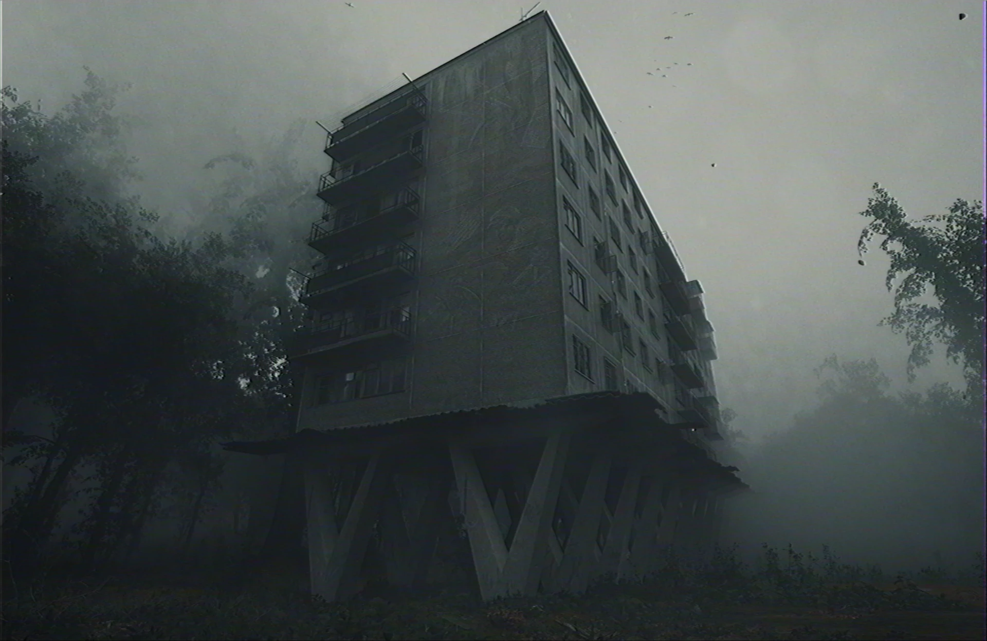 Tall concrete block on stilts in fog with trees — full frame