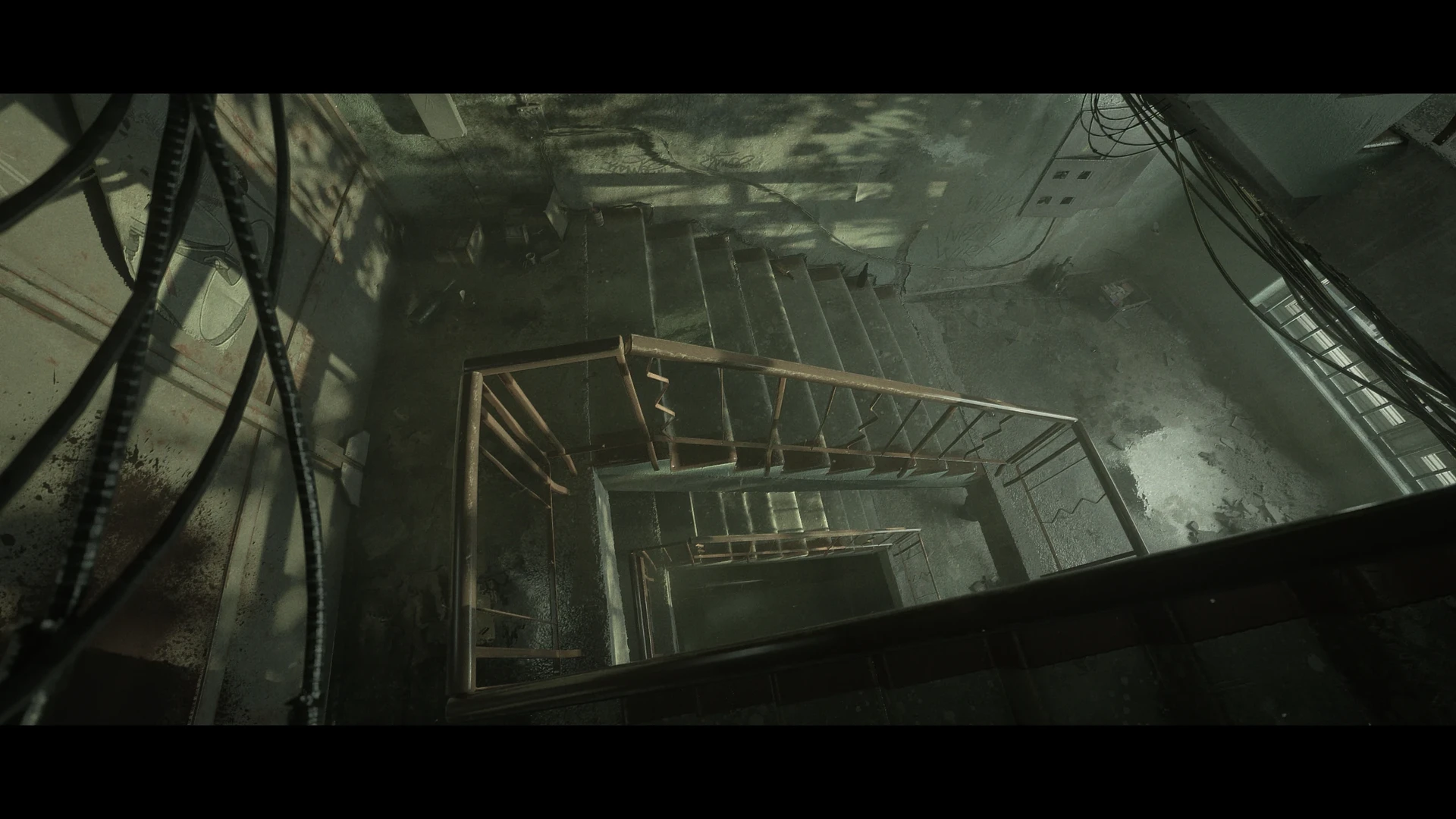 Top-down concrete stairwell with rust rails and cables — full frame